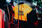 Yellow sports jersey with 'Vino Disco' branding on a rack in a store.