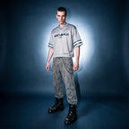 Model in gray boxy striped soccer jersey by Merch in Town x Guillaume Michaud, styled with vintage wash leopard pants and black platform boots.