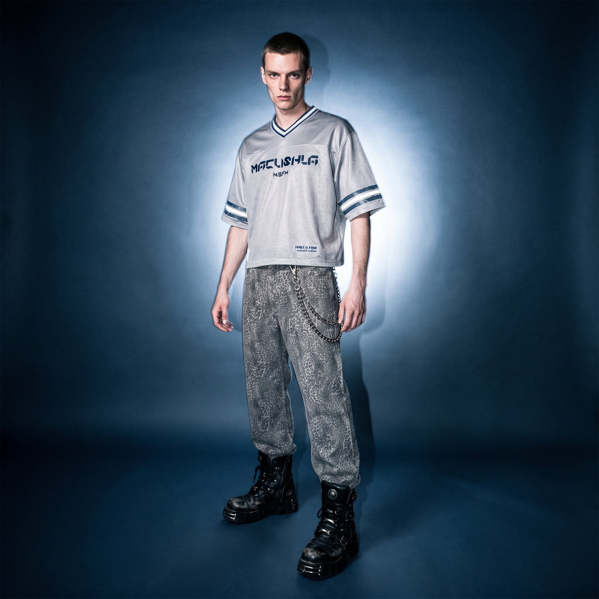 Model in gray boxy striped soccer jersey by Merch in Town x Guillaume Michaud, styled with vintage wash leopard pants and black platform boots.