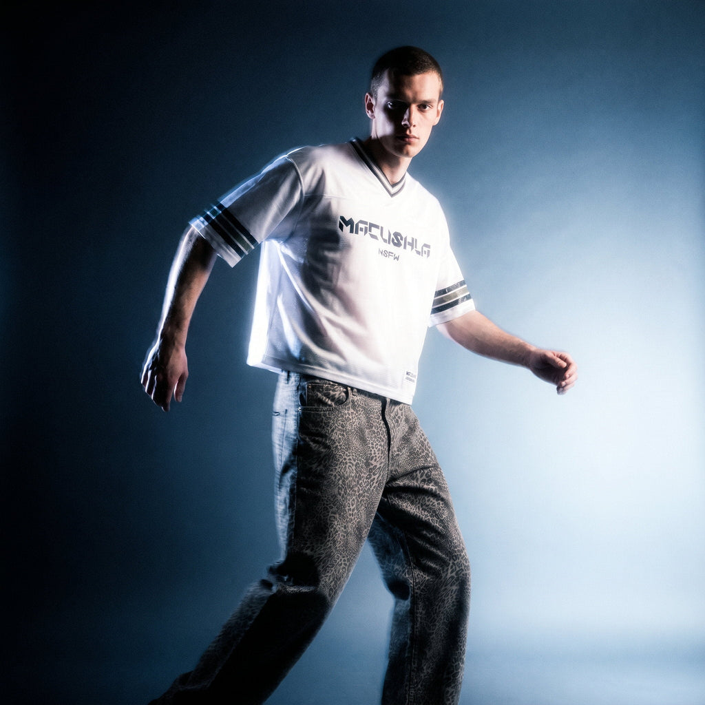 Model in white boxy striped soccer jersey by Merch in Town x Guillaume Michaud, styled with vintage wash leopard wide leg jeans, studio motion blur.