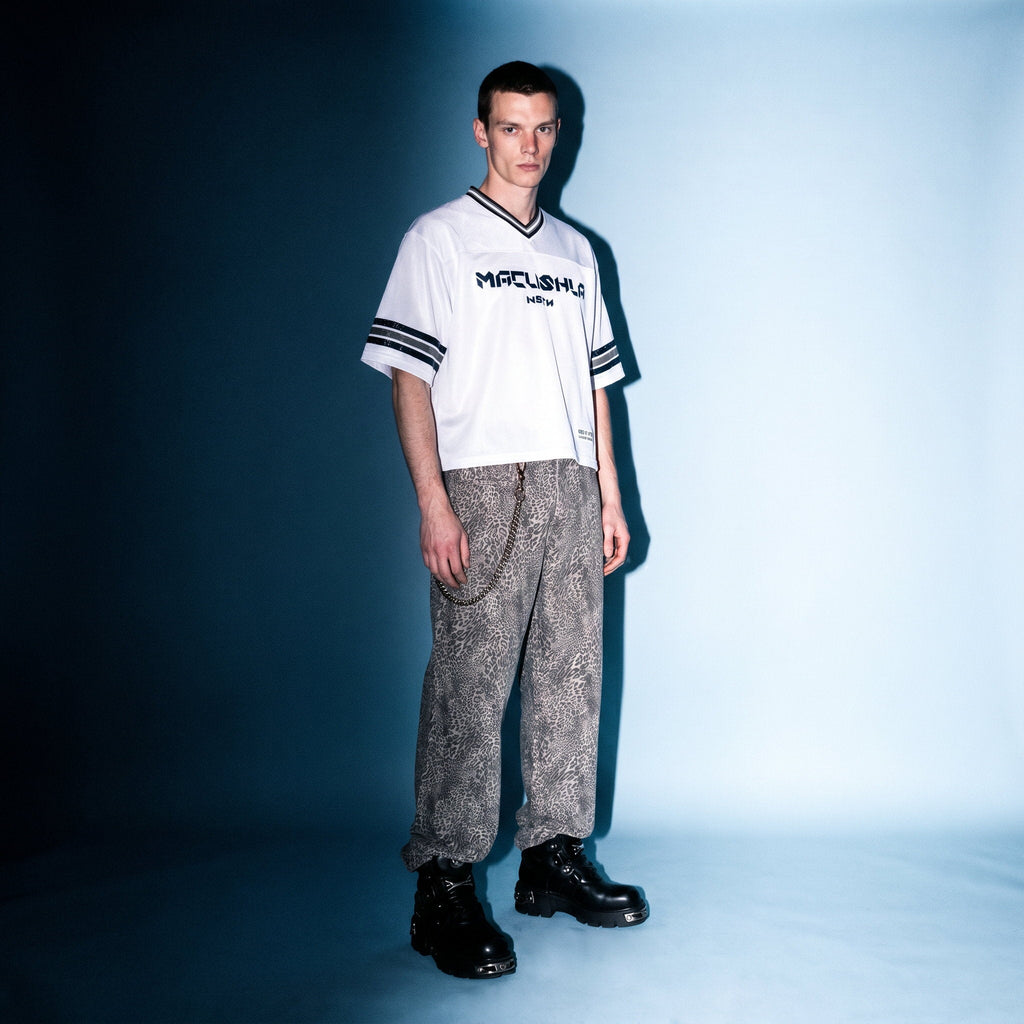 Model in white boxy striped soccer jersey by Merch in Town x Guillaume Michaud, styled with vintage wash leopard pants and buckled platform boots.