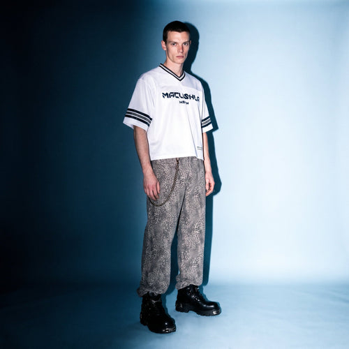 Model in white boxy striped soccer jersey by Merch in Town x Guillaume Michaud, styled with vintage wash leopard pants and buckled platform boots.