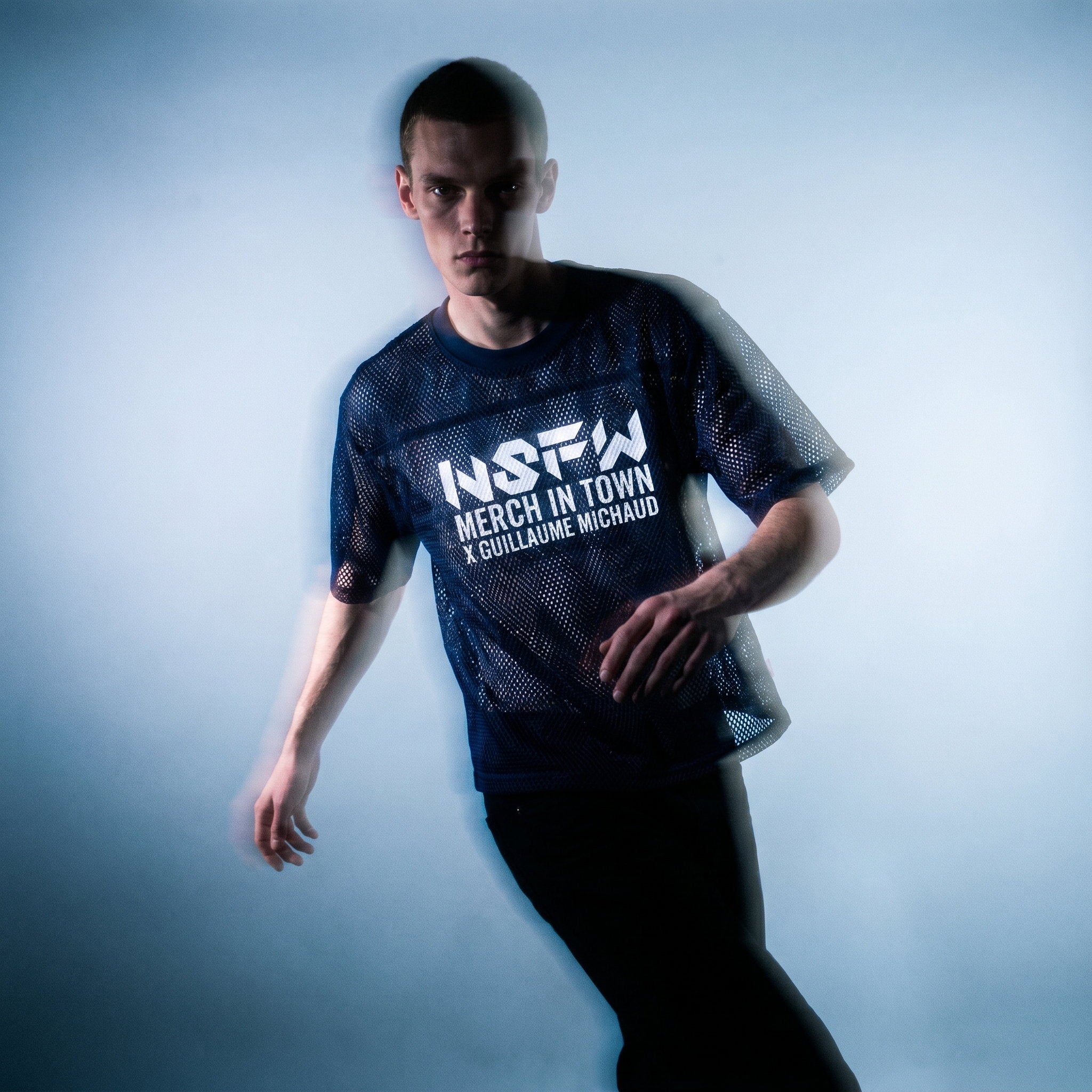 Motion-blur studio shot of the navy mesh NSFW tee by Merch in Town x Guillaume Michaud.