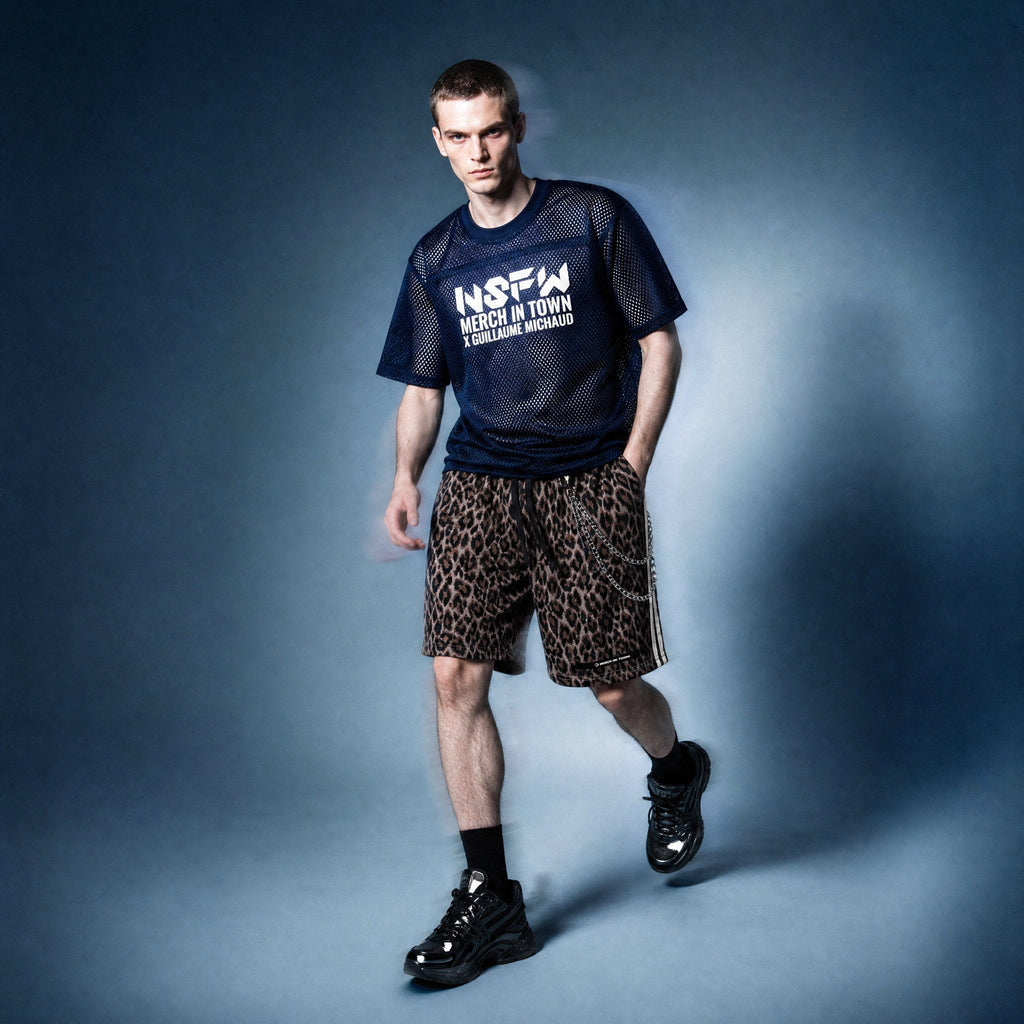 Model in navy mesh NSFW tee by Merch in Town x Guillaume Michaud, styled with leopard drawstring shorts, wallet chain and black sneakers.