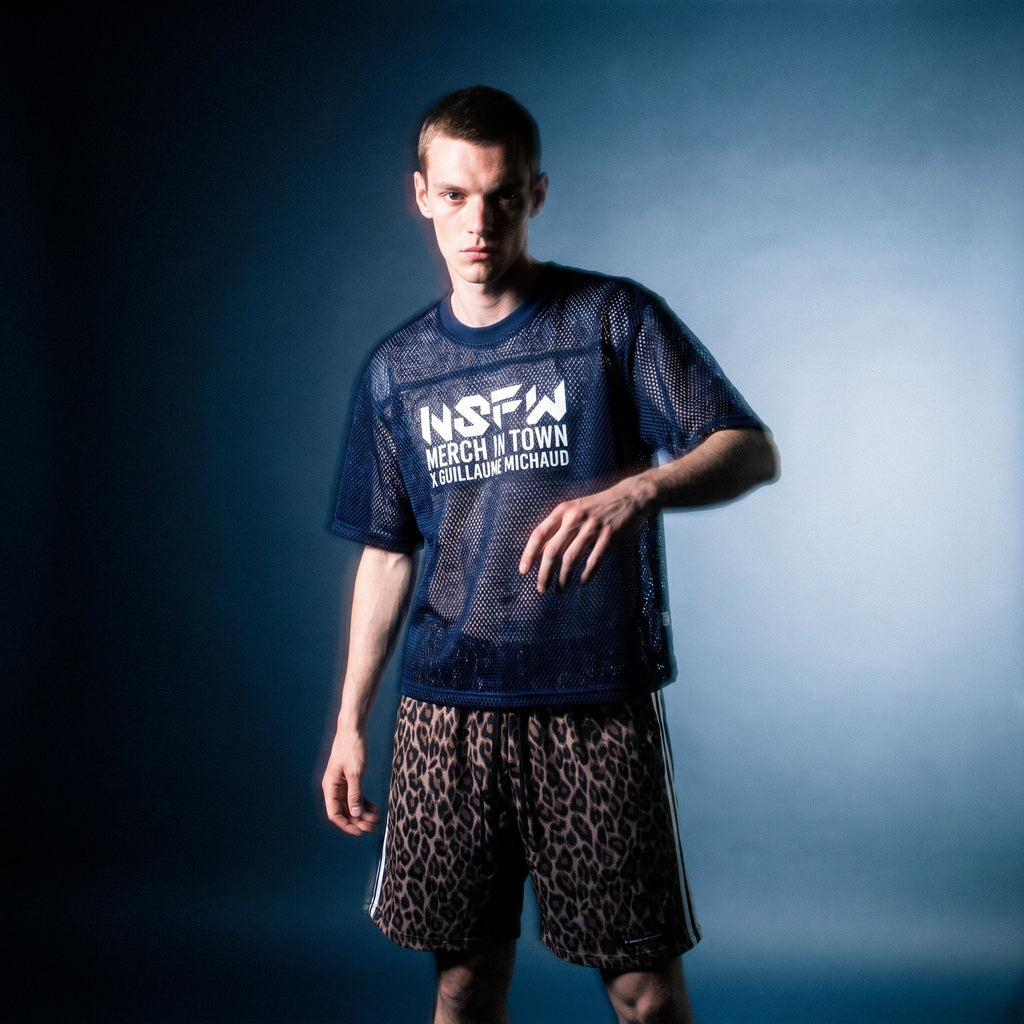 Model in navy mesh NSFW tee by Merch in Town x Guillaume Michaud with leopard drawstring shorts, studio motion blur.