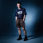 Full-length shot of the navy mesh NSFW tee by Merch in Town x Guillaume Michaud with leopard drawstring shorts and black sneakers.