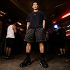 Model in Merch in Town leopard drawstring shorts and a mineral wash tee at an underground club.