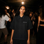 Person in a Merch in Town Vintage Wash Drop Shoulder Lyocell Shirt in Black in a dimly lit club.