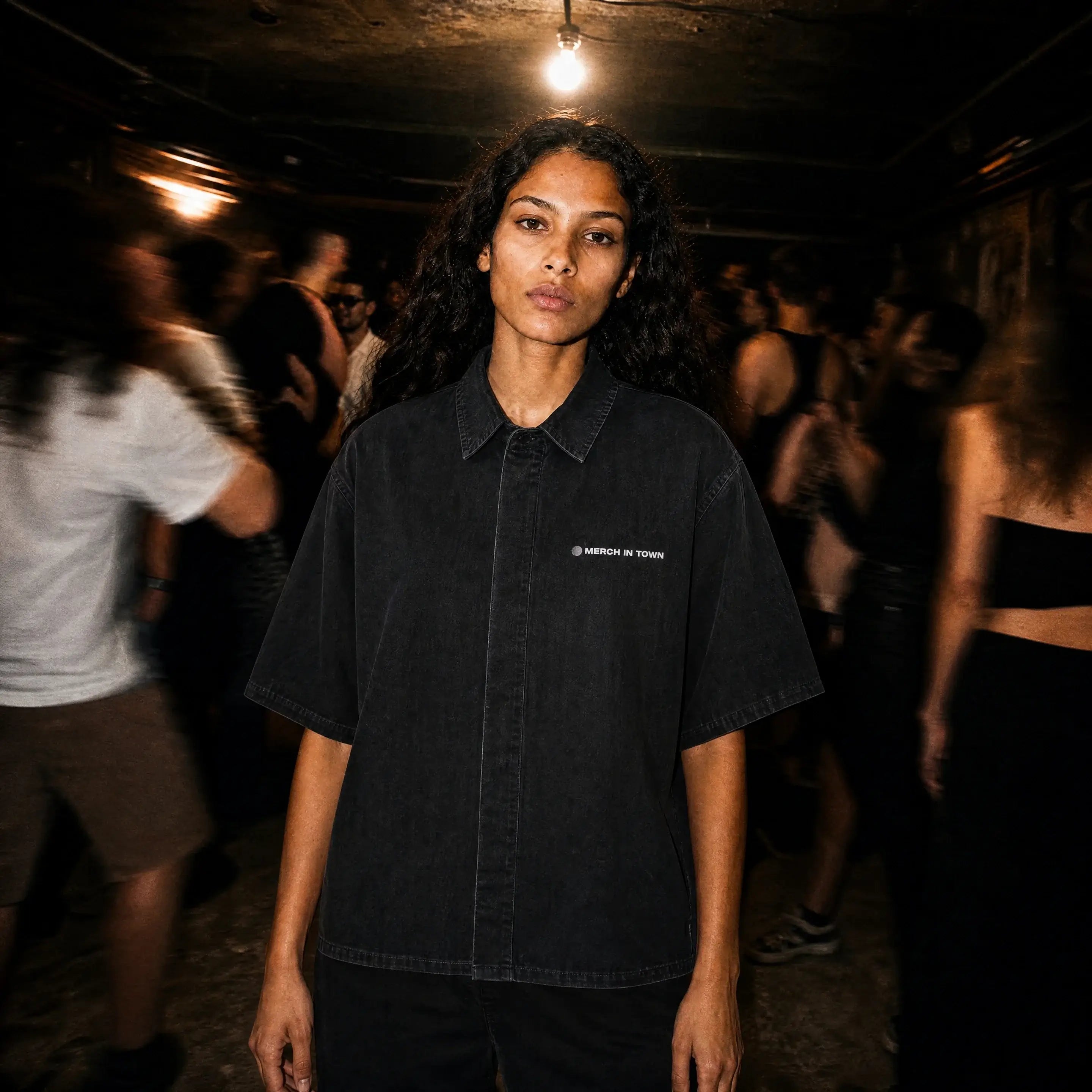 Person in a Merch in Town Vintage Wash Drop Shoulder Lyocell Shirt in Black in a dimly lit club.