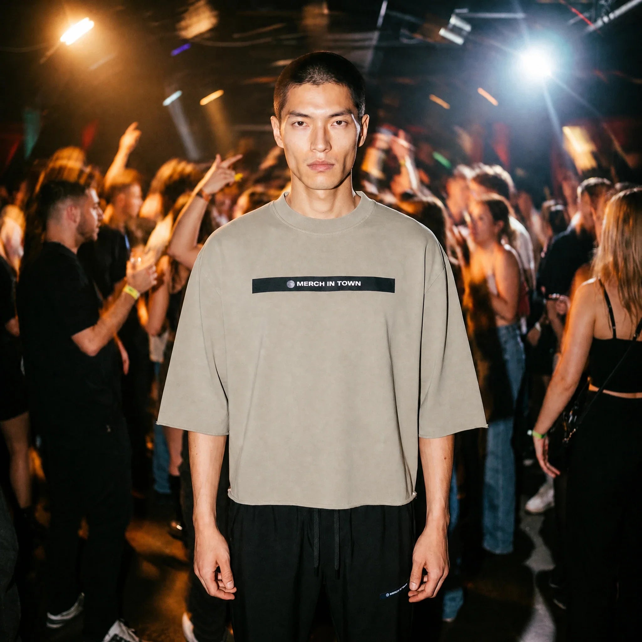 Model in a Merch in Town mineral wash raw hem boxy tee in apricot at an underground club.