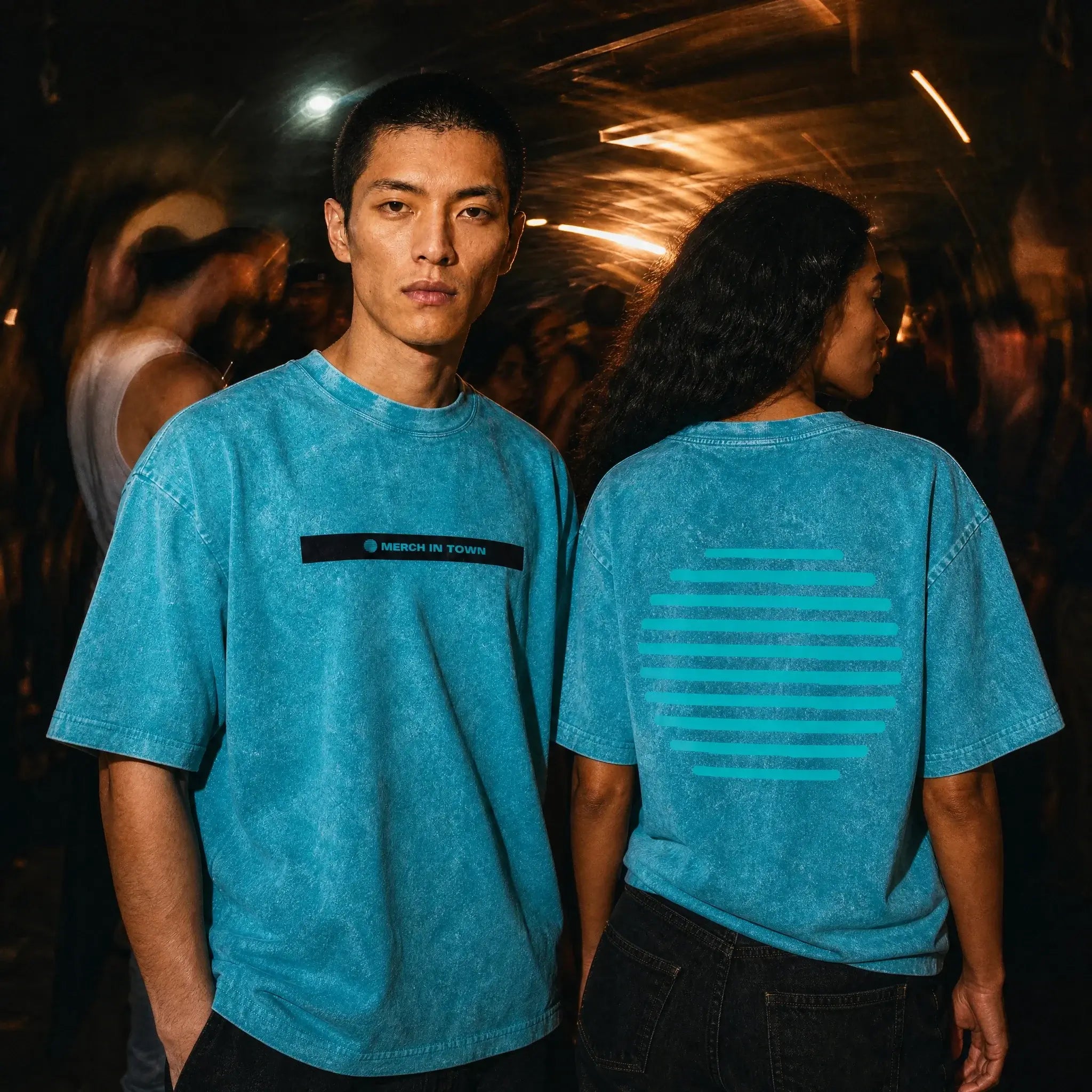Two people in Merch in Town Snow Washed Signature Stripe tees in a dark club setting, one front and one back.