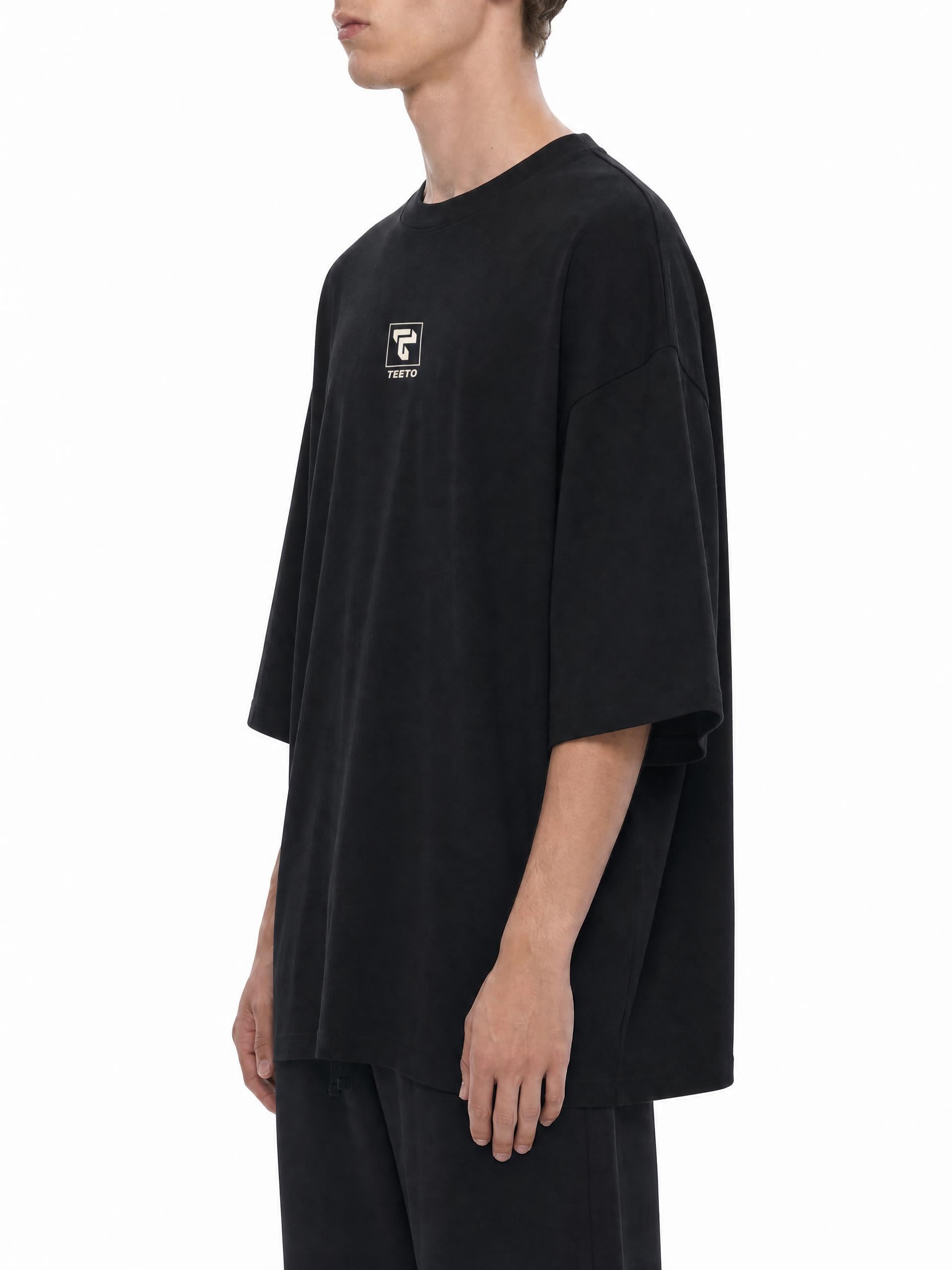 Teeto Oversized Drop Shoulder T-Shirt in Black worn by a model, side view.