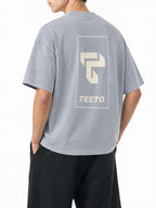 Teeto Mineral Wash Boxy Cotton T-Shirt in Light Gray worn by a model, back view with TEETO back logo.